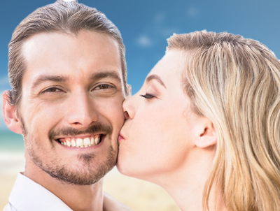Man smiling while woman kisses his cheek